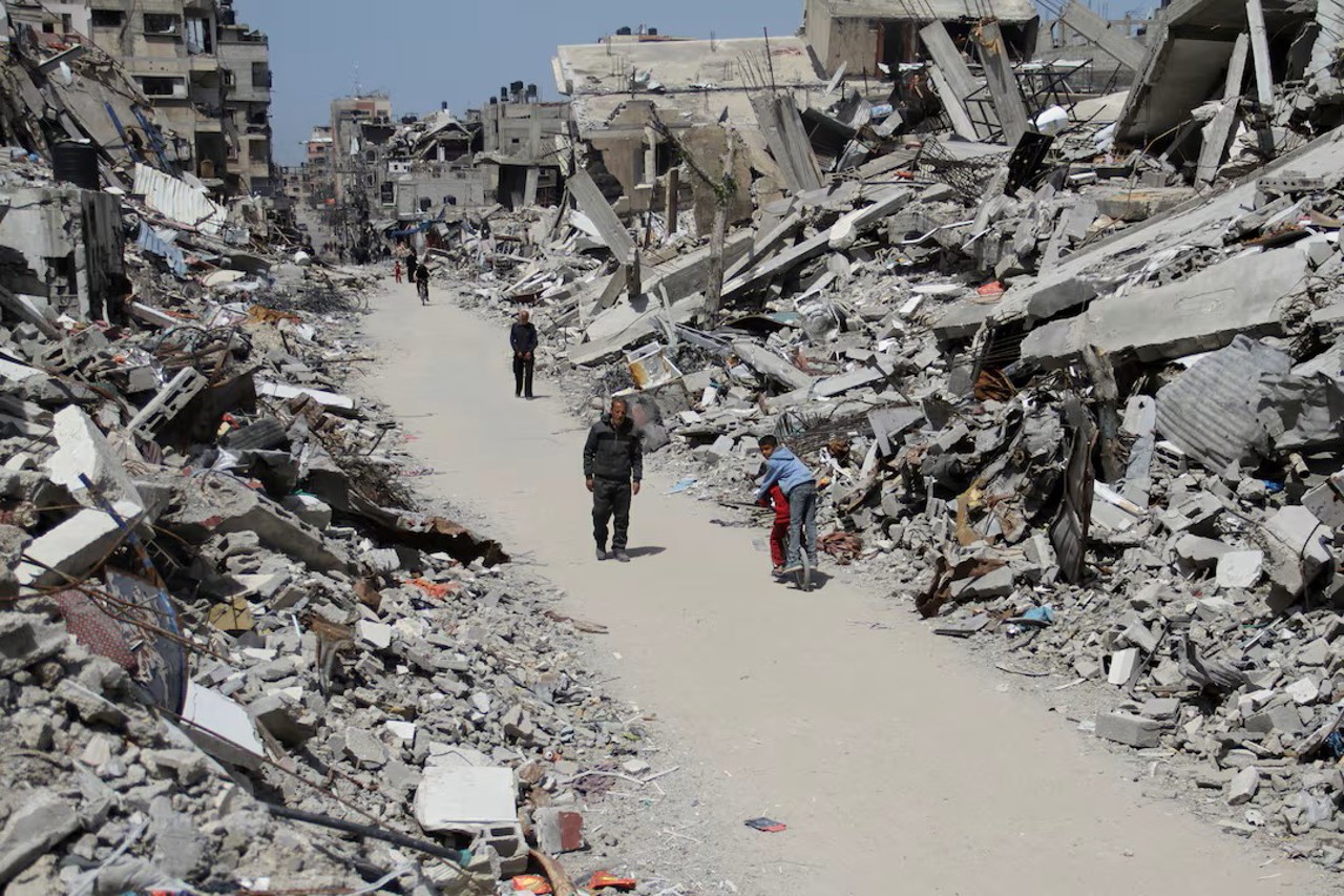 Reuters / Palestinieni trec pe lângă ruinele unor case în nordul Fâșiei Gaza 31 martie 2024
