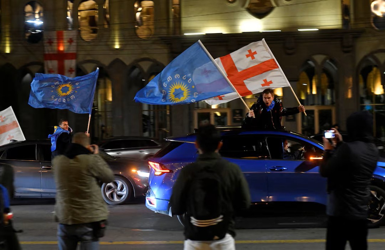 Reuters / Susținători ai partidului Visul Georgian flutură steaguri georgiene și steaguri ale partidului din mașini după anunțarea rezultatelor exit-poll-ului în alegerile parlamentare, în Tbilisi, Georgia, 26 octombrie 2024.