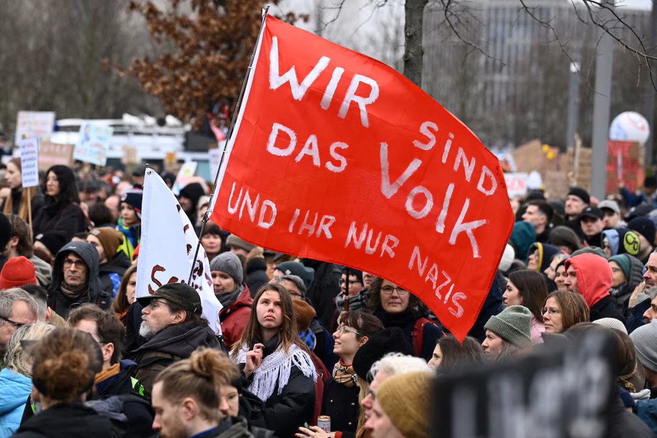 Reuters / Oamenii se adună în timpul unui miting al alianței largi „Hand in Hand” sub sloganul „Wir sind die Brandmauer” („Noi suntem zidul de foc”) pentru a protesta împotriva extremismului de dreapta și pentru protejarea democrației, în Berlin, Germania, 3 februarie 2024. În text se poate citi: „Noi suntem poporul și voi sunteți doar naziști”