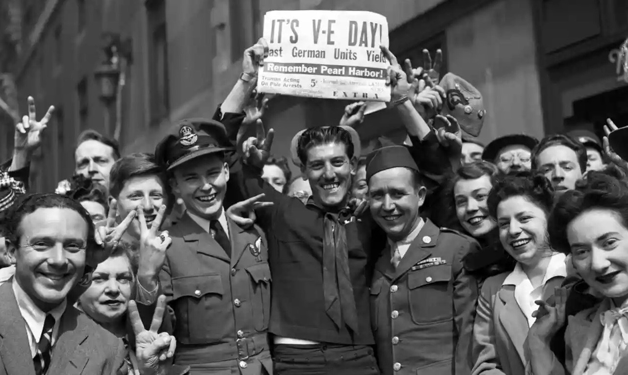 The Guardian / O mulțime sărbătorește ziua VE care marchează capitularea Germaniei în cel de-al doilea război mondial, mai 1945.